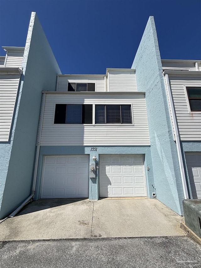 view of front of home with an attached garage, driveway, and stucco siding