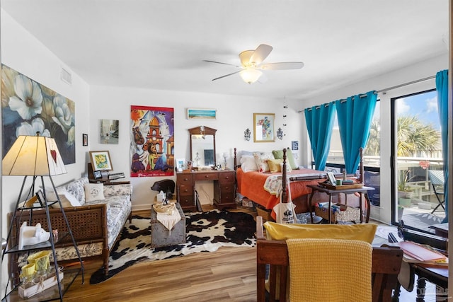 interior space featuring ceiling fan, access to exterior, wood finished floors, and visible vents
