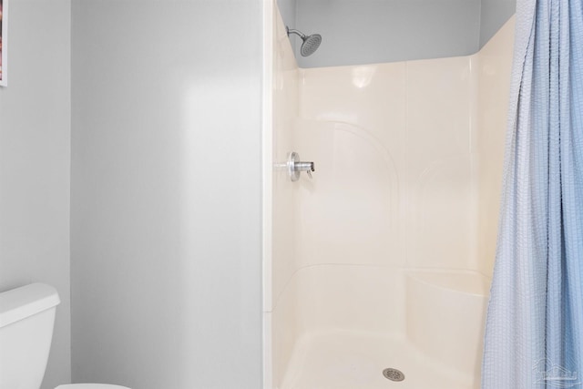 bathroom featuring a stall shower and toilet