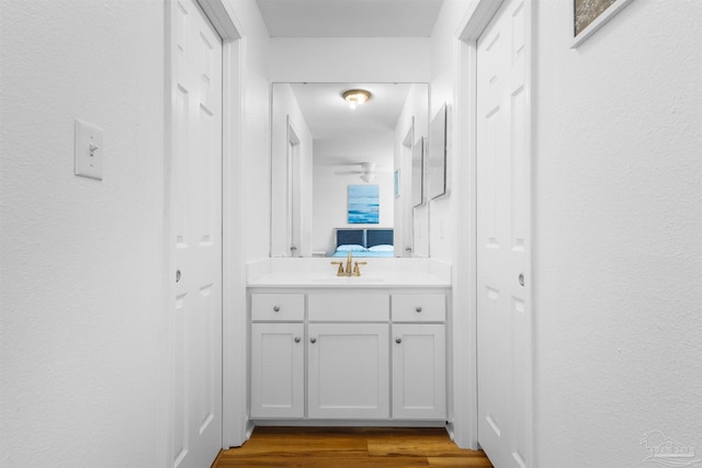 ensuite bathroom with vanity, wood finished floors, and connected bathroom