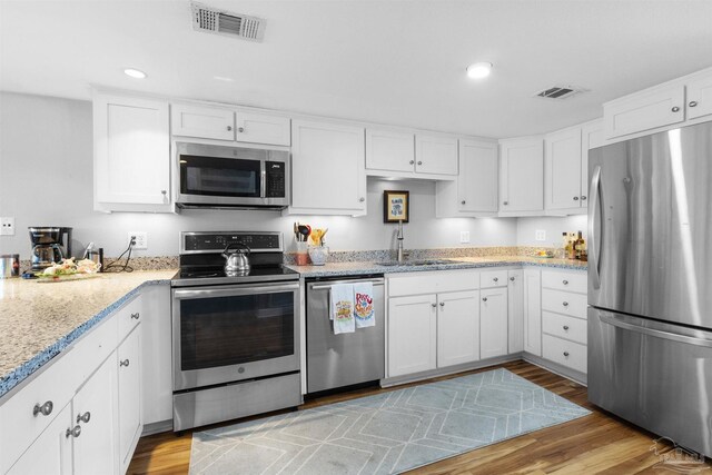 kitchen with stainless steel appliances, visible vents, a sink, and light wood-type flooring