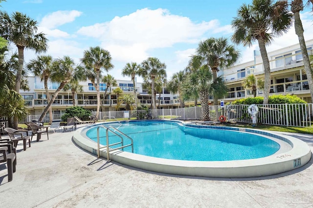 community pool with fence and a patio area