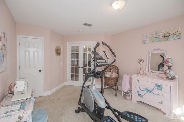 exercise room featuring light carpet and french doors