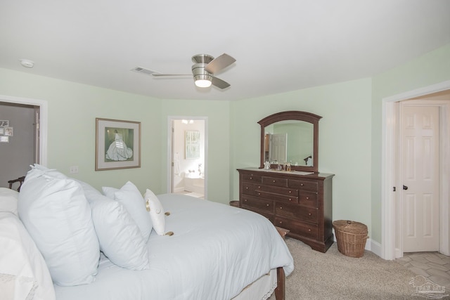 bedroom featuring ceiling fan, light colored carpet, and connected bathroom