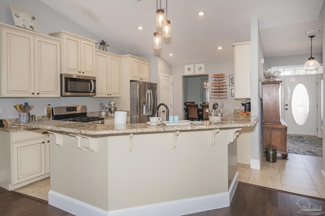 kitchen with hanging light fixtures, a kitchen bar, light stone countertops, and stainless steel appliances