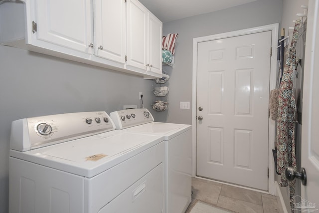 clothes washing area with washing machine and dryer, cabinets, and light tile patterned floors