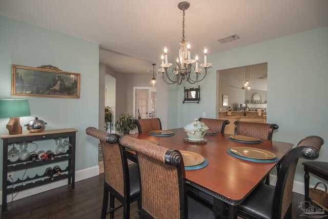 dining area featuring french doors, dark wood-type flooring, sink, and a chandelier