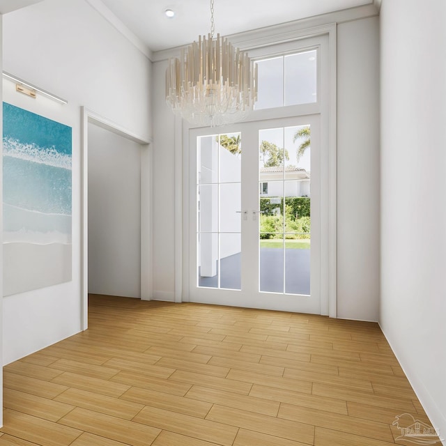 doorway to outside featuring light wood-type flooring and a notable chandelier