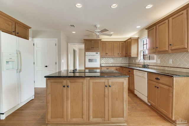 kitchen featuring white appliances, visible vents, light wood-style flooring, a kitchen island, and a sink