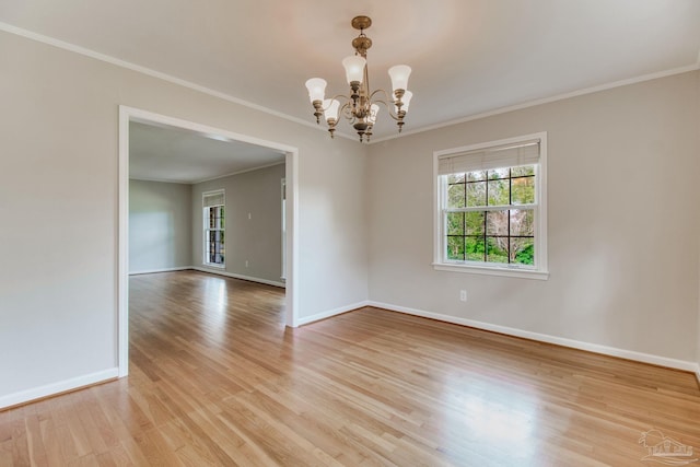 empty room featuring light wood finished floors, a notable chandelier, baseboards, and crown molding