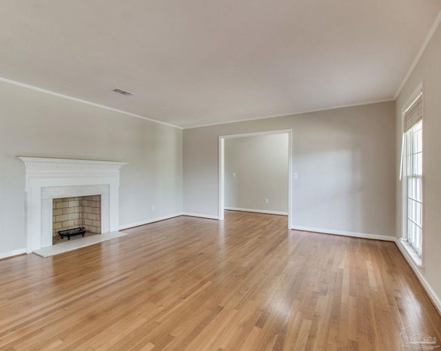 unfurnished living room featuring visible vents, a fireplace with flush hearth, light wood-style floors, ornamental molding, and baseboards