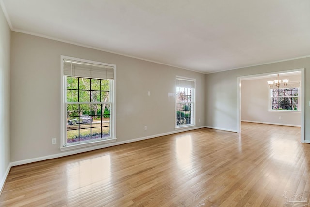 empty room featuring ornamental molding, light wood-style floors, baseboards, and a notable chandelier