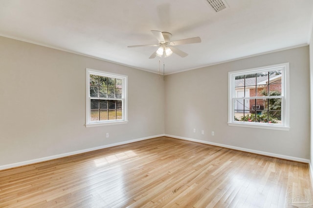 spare room with light wood finished floors, a wealth of natural light, visible vents, and baseboards