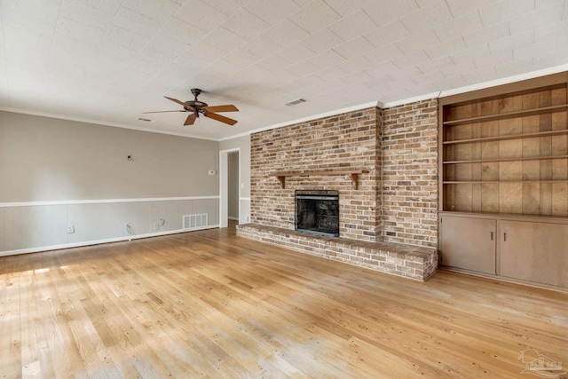 unfurnished living room with visible vents, built in shelves, a fireplace, and hardwood / wood-style floors