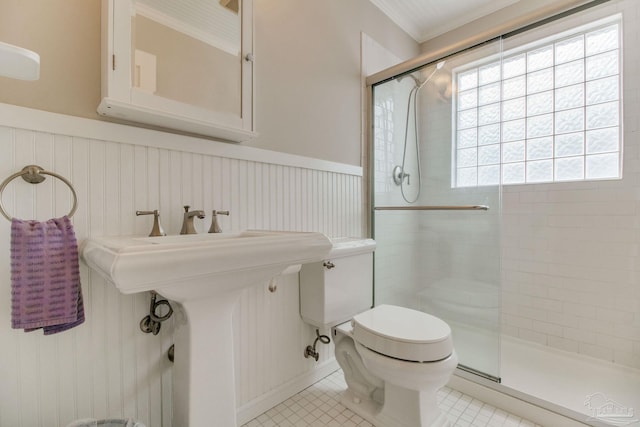 full bath featuring a stall shower, wainscoting, toilet, ornamental molding, and tile patterned floors