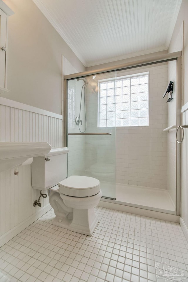 bathroom with a wainscoted wall, crown molding, a shower stall, and toilet