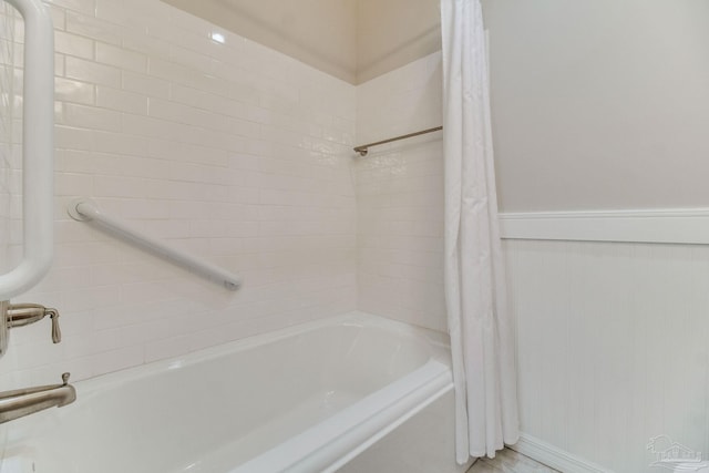 full bathroom with shower / tub combo and a wainscoted wall