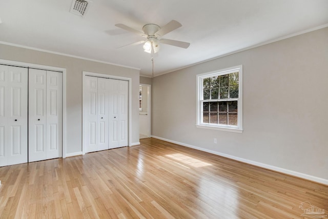 unfurnished bedroom with multiple closets, visible vents, light wood-style floors, and baseboards