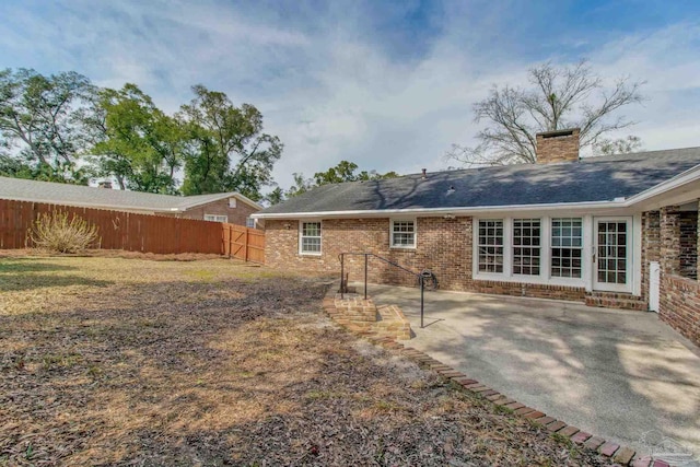 back of house featuring a chimney, fence, a patio, and brick siding