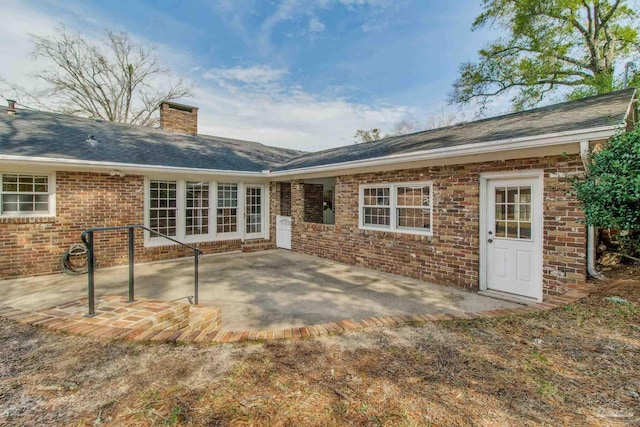 back of property with a chimney, a patio, and brick siding