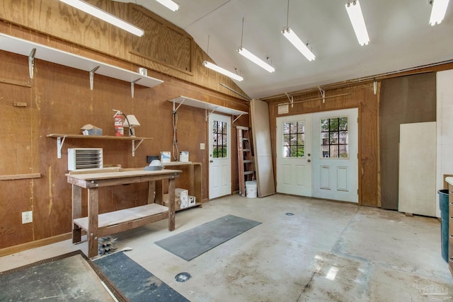 miscellaneous room featuring concrete flooring, french doors, high vaulted ceiling, and wooden walls