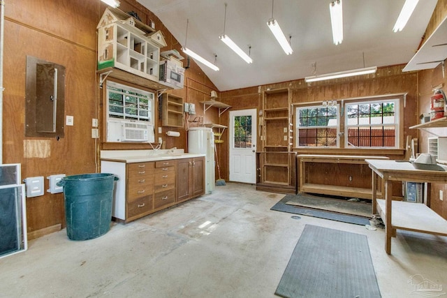 miscellaneous room with water heater, concrete floors, wooden walls, and a workshop area