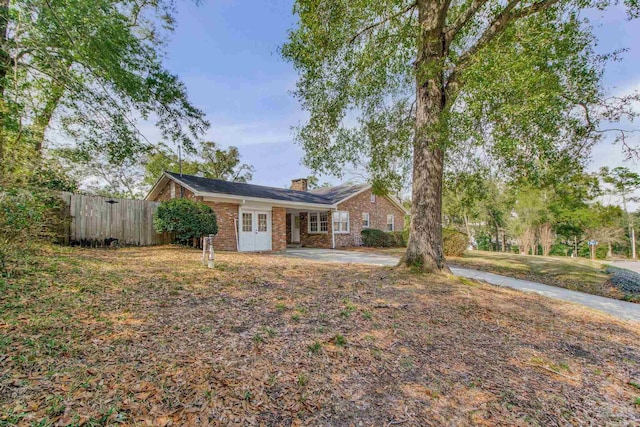 view of front of home featuring french doors, brick siding, fence, and a chimney