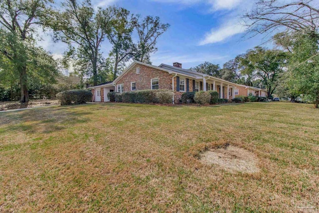 view of front of home with brick siding, a chimney, and a front lawn