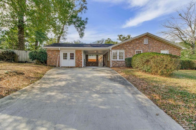 ranch-style home featuring concrete driveway, brick siding, and fence