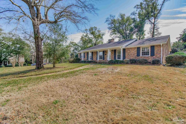 ranch-style house with brick siding, a chimney, and a front lawn