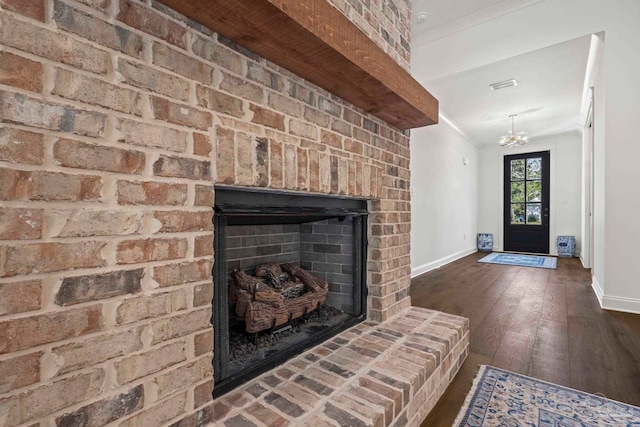 living room featuring a notable chandelier, dark wood-type flooring, and a brick fireplace