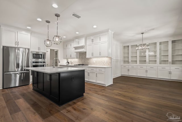 kitchen with appliances with stainless steel finishes, dark hardwood / wood-style flooring, a kitchen island with sink, and pendant lighting