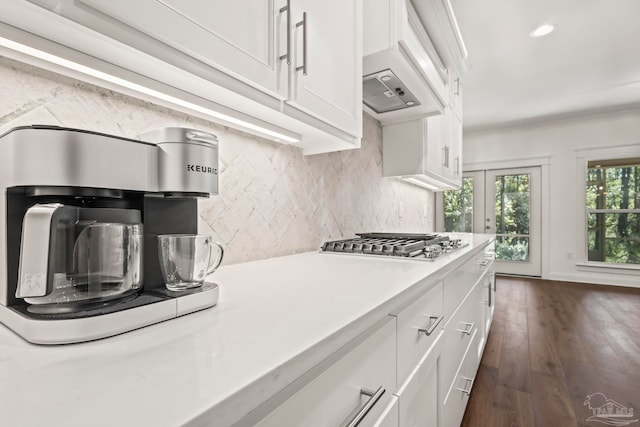 kitchen featuring decorative backsplash, stainless steel gas cooktop, custom range hood, white cabinetry, and dark hardwood / wood-style flooring