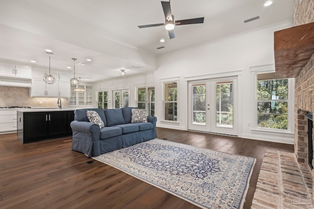 living room with ceiling fan, dark hardwood / wood-style flooring, a fireplace, french doors, and sink