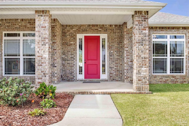 doorway to property with covered porch and a lawn