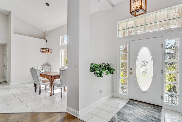 foyer entrance featuring baseboards, high vaulted ceiling, and a healthy amount of sunlight