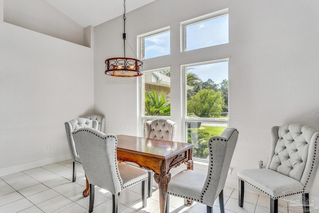 dining space with light tile patterned floors, baseboards, and high vaulted ceiling