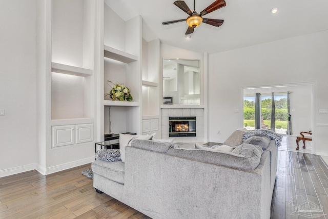 living area with ceiling fan, baseboards, wood finished floors, and a fireplace