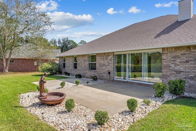 back of property featuring a patio area, a yard, brick siding, and roof with shingles