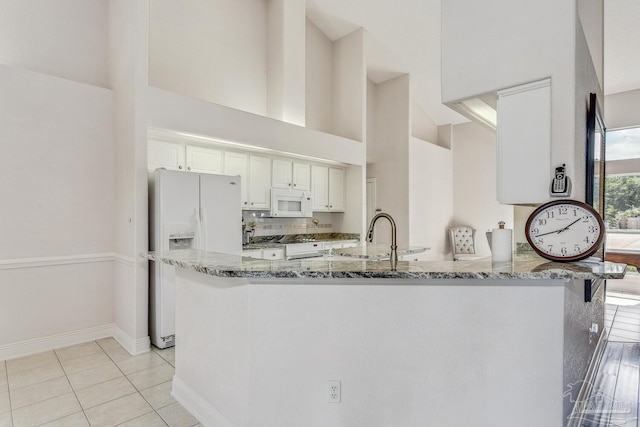 kitchen with stone countertops, white appliances, white cabinetry, and a sink