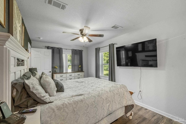 bedroom featuring visible vents, baseboards, a textured ceiling, and wood finished floors