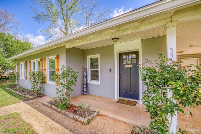 property entrance featuring a porch and stucco siding