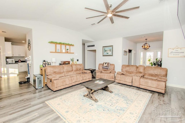 living room with vaulted ceiling, ceiling fan with notable chandelier, and light hardwood / wood-style floors