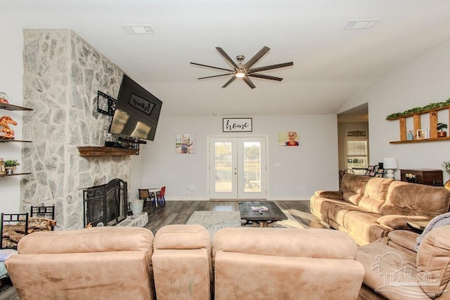 living room with french doors, ceiling fan, hardwood / wood-style floors, and a stone fireplace