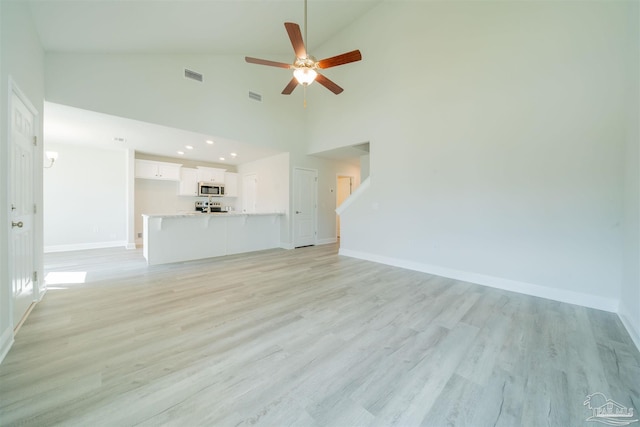 unfurnished living room with ceiling fan, high vaulted ceiling, and light hardwood / wood-style floors