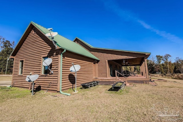 view of side of home featuring a deck, metal roof, and a yard