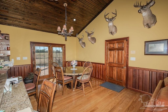 dining room with light wood-style flooring, wood ceiling, french doors, wainscoting, and an inviting chandelier