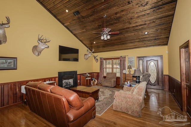 living area featuring wooden ceiling, wainscoting, a multi sided fireplace, and wood finished floors