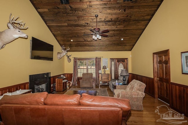 living room featuring wooden walls, wainscoting, wood ceiling, vaulted ceiling, and a fireplace