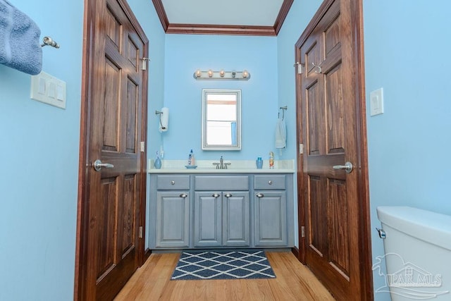 bathroom featuring toilet, vanity, crown molding, and wood finished floors